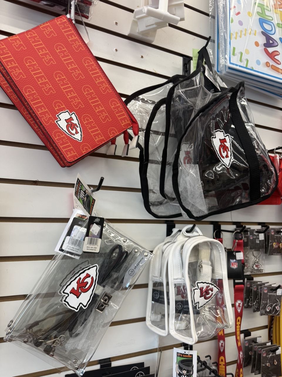 Kansas City Chiefs clear bags, purses, and red patterned zip bag on display.
