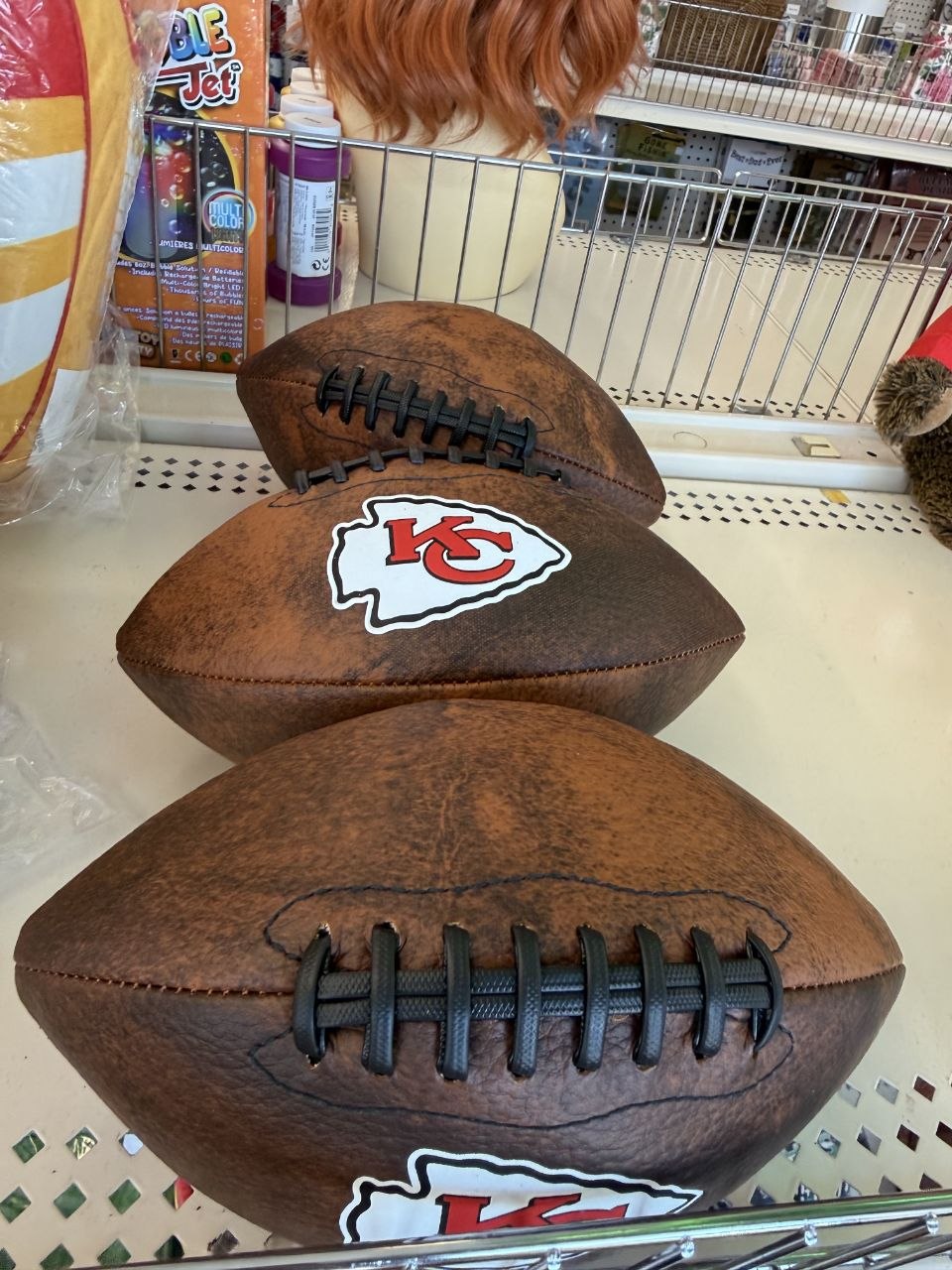 Plush football decorations including two with Kansas City Chiefs arrowhead logos.