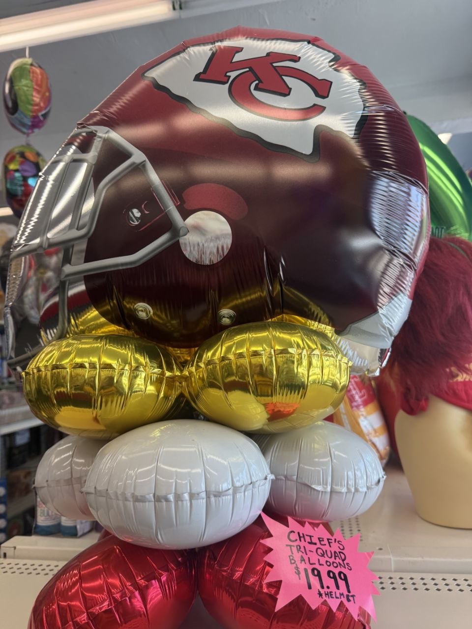 Chiefs helmet balloon bouquet stacked with football-shaped balloons at the store counter.